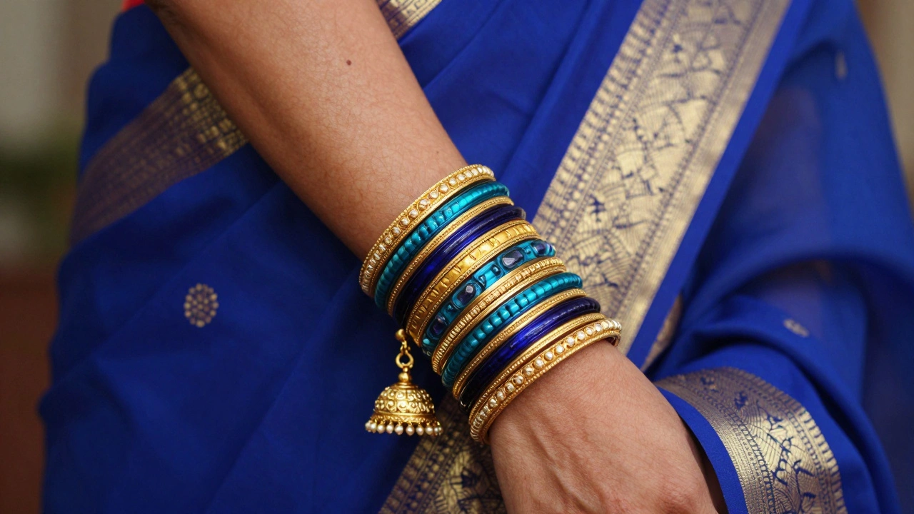 Close-up of colorful glass bangles and gold Jhumka earrings against a blue silk saree